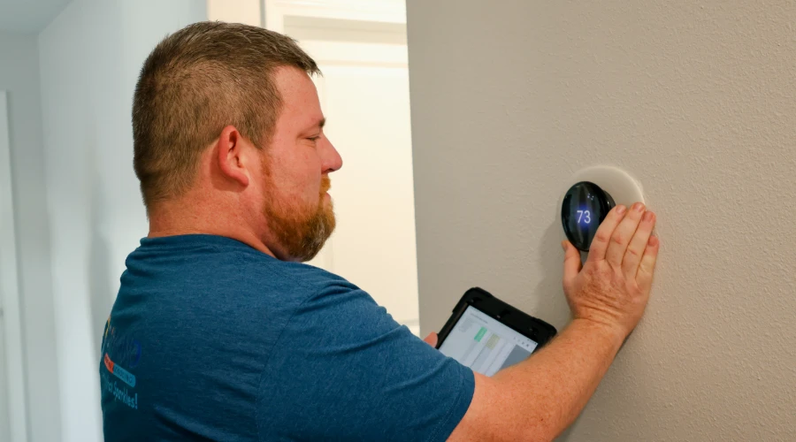 Dymond Heating & Cooling Technician Calibrating A Smart Thermostat.